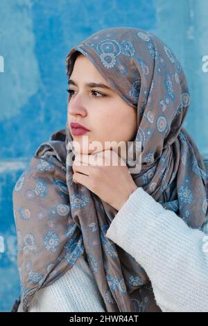 Jeune femme réfléchie dans le hijab devant le mur Banque D'Images