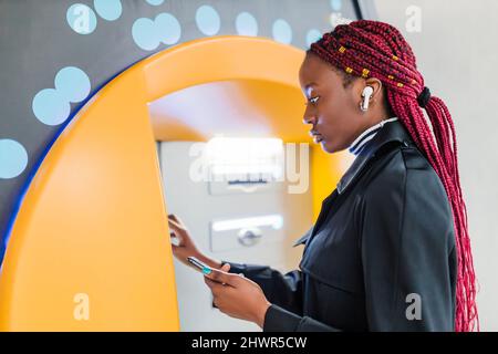 Young woman using ATM machine Banque D'Images