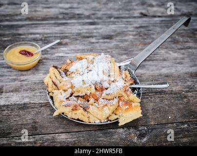 Kaiserschmarren servi dans une casserole avec une sauce aux pommes sur une table en bois Banque D'Images