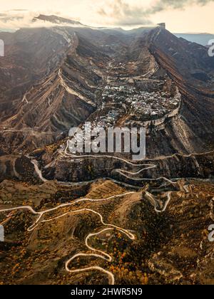 Russie, Dagestan, Gunib, Winding route de montagne en automne avec Mont Gunib et village en arrière-plan Banque D'Images