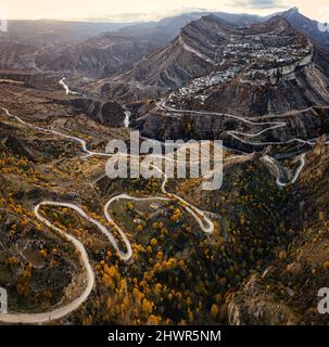 Russie, Dagestan, Gunib, Winding route de montagne en automne avec Mont Gunib et village en arrière-plan Banque D'Images