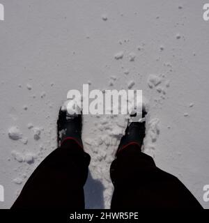 Homme marchant sur un terrain enneigé. Homme marchant avec des bottes sur ses pieds. Banque D'Images