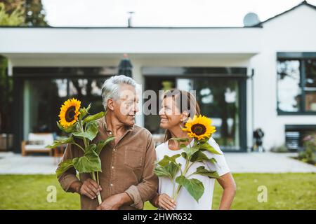 Couple heureux avec des tournesols regardant l'un l'autre dans le jardin Banque D'Images