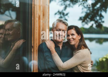 Couple souriant debout près d'un mur de verre Banque D'Images