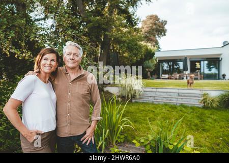 Femme souriante aux cheveux bruns debout par l'homme à l'arrière-cour Banque D'Images