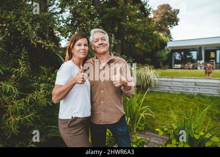 Homme et femme souriants qui font des gestes à l'arrière-cour Banque D'Images