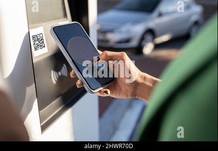 Commuter scannant le code QR sur le smartphone à la station-service Banque D'Images