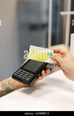 Femme effectuant un paiement sans contact par carte de crédit à la réception Banque D'Images