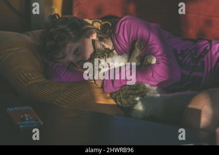 adorable fille blonde se détendant à l'intérieur avec un joli chat Banque D'Images