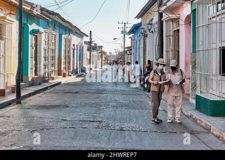 Rue avec des bâtiments colorés dans la vieille ville coloniale Trinidad, Cuba. Touristes asiatiques examinant la carte. Banque D'Images