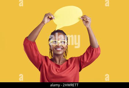 Bonne femme afro-américaine dans des lunettes tenant une bulle de pensée ou de discours Banque D'Images