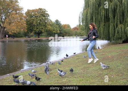 Fille qui court avec des pigeons dans le Regent Park de Londres Banque D'Images