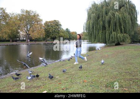 Fille qui court avec des pigeons dans le Regent Park de Londres Banque D'Images