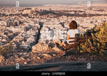 Femme assise sur la colline de Lycabette, le point le plus haut de la ville surplombant Athènes avec l'Acropole - voyageur du monde Banque D'Images