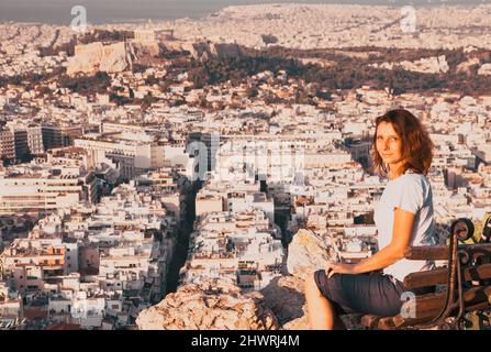 Femme assise sur la colline de Lycabette, le point le plus haut de la ville surplombant Athènes avec l'Acropole - voyageur du monde Banque D'Images