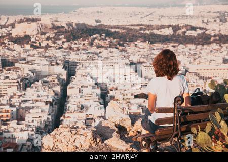 Femme avec une carte assise sur la colline de Lycabette, le point le plus haut de la ville surplombant Athènes avec l'Acropole - voyageur du monde Banque D'Images