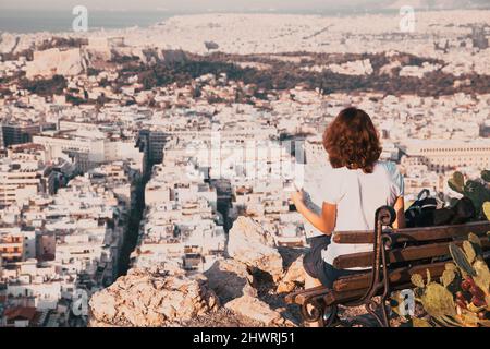 Femme avec une carte assise sur la colline de Lycabette, le point le plus haut de la ville surplombant Athènes avec l'Acropole - voyageur du monde Banque D'Images