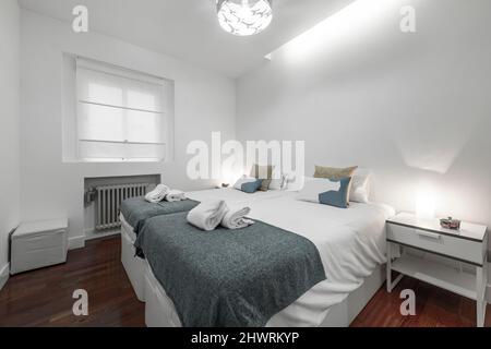 chambre avec lits doubles avec couettes blanches, stores assortis, petites couvertures bleues et tables de chevet avec deux lampes Banque D'Images