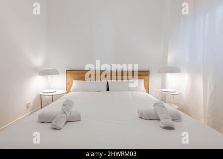 Chambre avec lit King Size, literie blanche, tête de lit en bois, finitions noires, lampes blanches et rideaux en lin blanc Banque D'Images