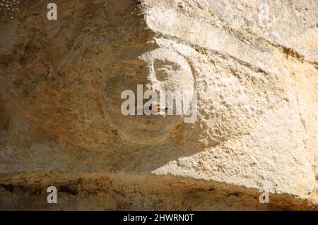 Dépendance au tabagisme. Pierre visage humain (vieux bâtiment architectural détail) avec vraie cigarette dans la bouche.photo conceptuelle. Banque D'Images