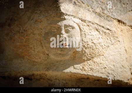 Dépendance au tabagisme. Pierre visage humain (vieux bâtiment architectural détail) avec vraie cigarette dans la bouche.photo conceptuelle. Banque D'Images