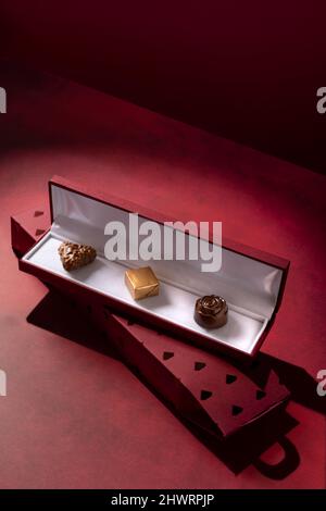 Le cadeau parfait d'une boîte à bijoux avec sélection de pralines au chocolat en pierres précieuses de différentes formes sur fond rouge Banque D'Images