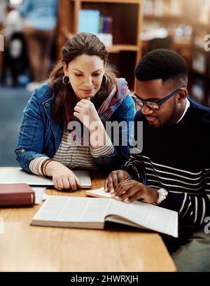Passer à la page suivante. Photo d'un groupe d'étudiants universitaires travaillant dans la bibliothèque du campus. Banque D'Images