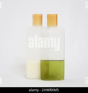 les produits de bain comme le shampooing et l'huile verte dans des bouteilles transparentes isolées dans un fond blanc Banque D'Images