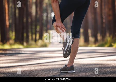 Une femme ressent des douleurs à la jambe pendant le jogging. Crampes de muscle de mollet. Sous-estimer l'exercice de préchauffage avant de courir Banque D'Images