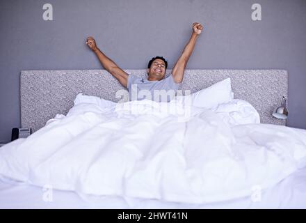 Les meilleures nuits de sommeil de ma vie. Un jeune homme s'étirant tout en se réveillant. Banque D'Images