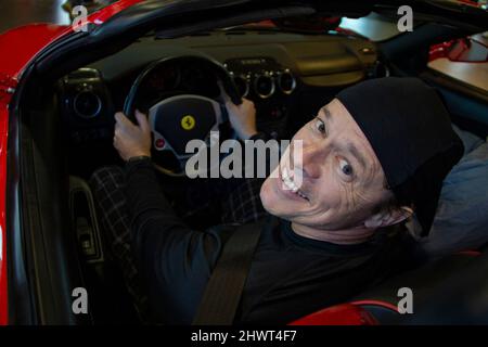 Heureux homme assis dans une voiture Ferrari. Moteur de voiture Ferrari. Banque D'Images