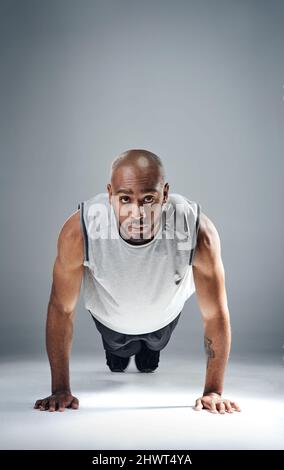 Poussez-vous quand tout le monde vous fait tomber. Photo d'un jeune homme sportif faisant des retouches sur fond gris. Banque D'Images