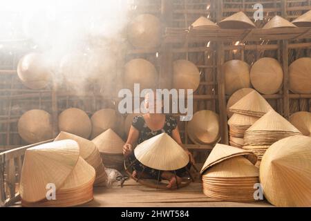 vieille femme vietnamienne faisant un chapeau conique traditionnel à sa maison Banque D'Images