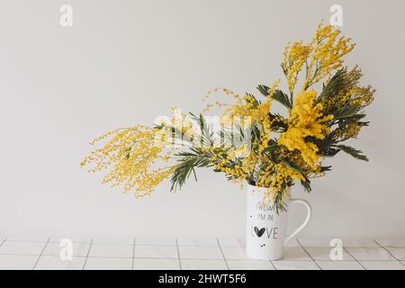 Bouquet Mimosa dans un vase sur fond clair avec espace de copie Banque D'Images