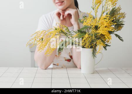Belle jeune femme souriante avec fleurs mimosa sur fond blanc. Banque D'Images