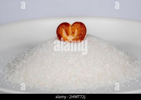 Biscuits en forme de coeurs en tas de sucre dans la plaque blanche Banque D'Images