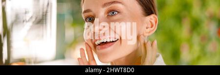 Gros plan portrait d'une jeune femme magnifique avec une peau lisse souriante tout en ayant la routine de beauté dans la salle de bains Banque D'Images