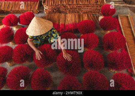 Encens en plein air de séchage avec vietnamienne portant chapeau conique dans le nord du Vietnam Banque D'Images