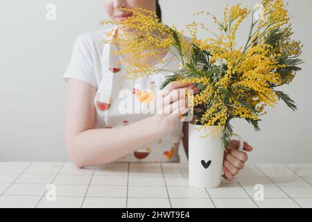 Belle jeune femme souriante avec fleurs mimosa sur fond blanc. Banque D'Images