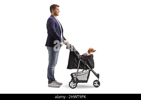 Photo de profil sur toute la longueur d'un jeune homme debout avec un chien de beagle dans une poussette isolée sur fond blanc Banque D'Images