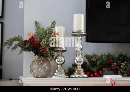 Manteau de Noël blanc décoré avec guirlande de pins, chandeliers en argent avec bougies et télévision Banque D'Images