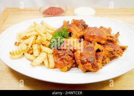 Un plateau de frites servi et des ailes de Buffalo cuites au four épicé Banque D'Images