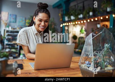 Un joli fleuriste plein d'esprit assis à l'ordinateur portable Banque D'Images