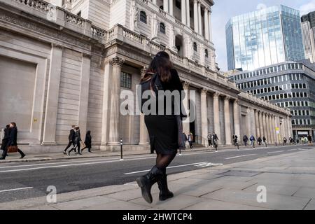 Passants à l'extérieur de la Banque d'Angleterre dans la Cité de Londres le 3rd mars 2022 à Londres, Royaume-Uni. La ville de Londres est une ville, un comté cérémonial et un quartier du gouvernement local qui contient le principal quartier central des affaires de Londres. La ville de Londres est largement connue sous le nom de « The City », également connu en commun sous le nom de « Square Mile ». Banque D'Images