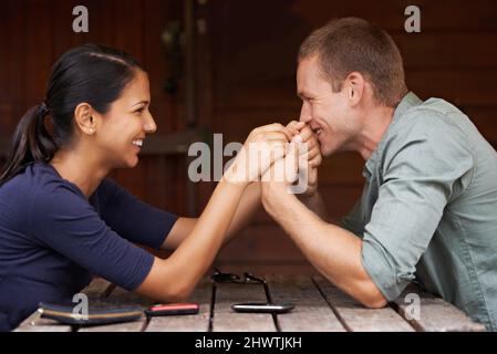 Je t'aime bébé. Un mignon couple multiracial assis ensemble et tenant les mains à l'extérieur. Banque D'Images