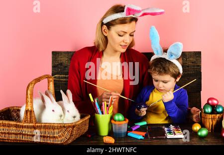 Mère et fils peignant des œufs de Pâques. Famille de lapins heureux avec des oreilles de lapin. Décoration aux œufs. Banque D'Images