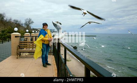 Femme adulte mature avec des aliments mouettes sur le remblai à Odessa Ukraine. Arrêter la guerre en Ukraine. Banque D'Images