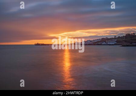 Un magnifique lever de soleil brille sur la mer douce de l'ancien quai swanage Banque D'Images