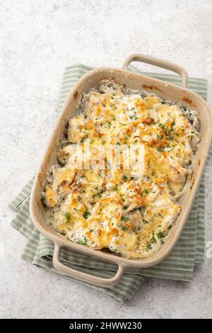 Cocotte de poisson blanc, chou-fleur, pomme de terre au fromage, crème sure et oignon Banque D'Images