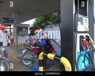 Caloocan, Philippines. 7th mars 2022. Le préposé à l'essence tire sa pompe à gaz et il est flexible pour atteindre le réservoir de carburant de la moto.les Philippines connaissent la flambée des prix du pétrole et d'autres produits de carburant dans le conflit Russie-Ukraine. Le ministère de l'énergie avertit le public de se préparer à une augmentation du coût du carburant dans les jours à venir, et il a déclaré que cette répercussion sur les prix se produit non seulement aux Philippines, mais aussi dans d'autres parties du monde. Le Gouvernement philippin prépare un plan d'urgence pour subventionner les coûts du carburant pour le secteur des transports publics, les agriculteurs et les pêcheurs Banque D'Images